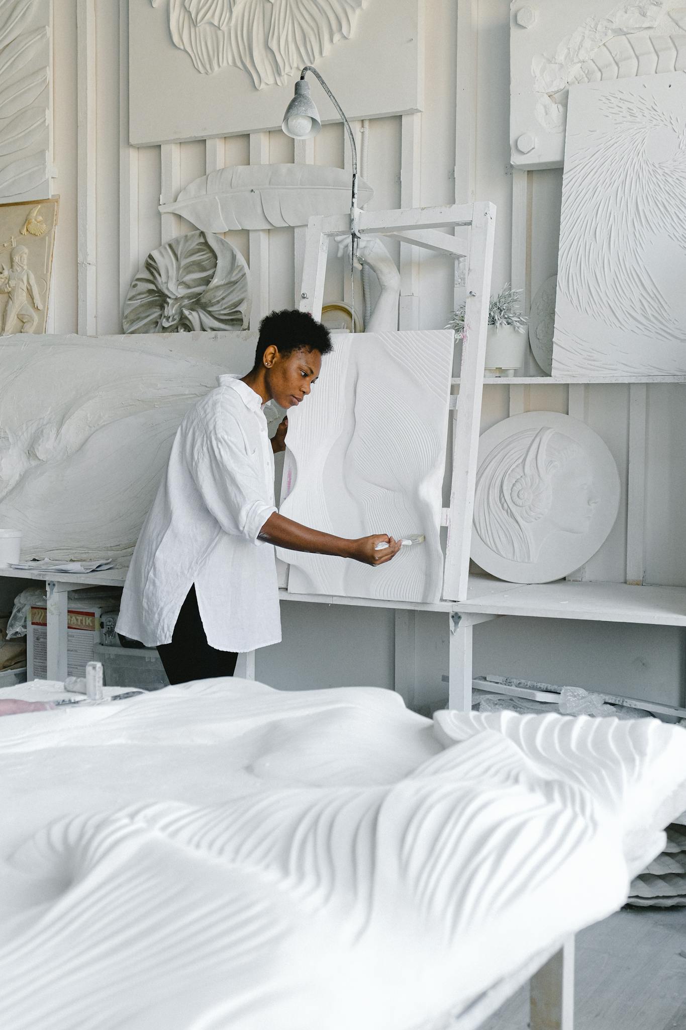 A woman artist meticulously works on an abstract sculptural piece in her studio.