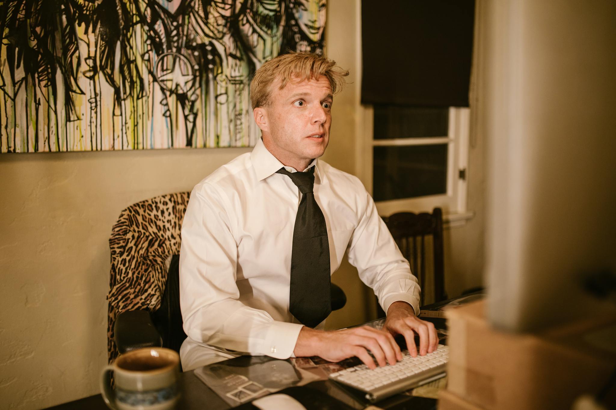 Businessman working late in home office with a serious expression, surrounded by art.